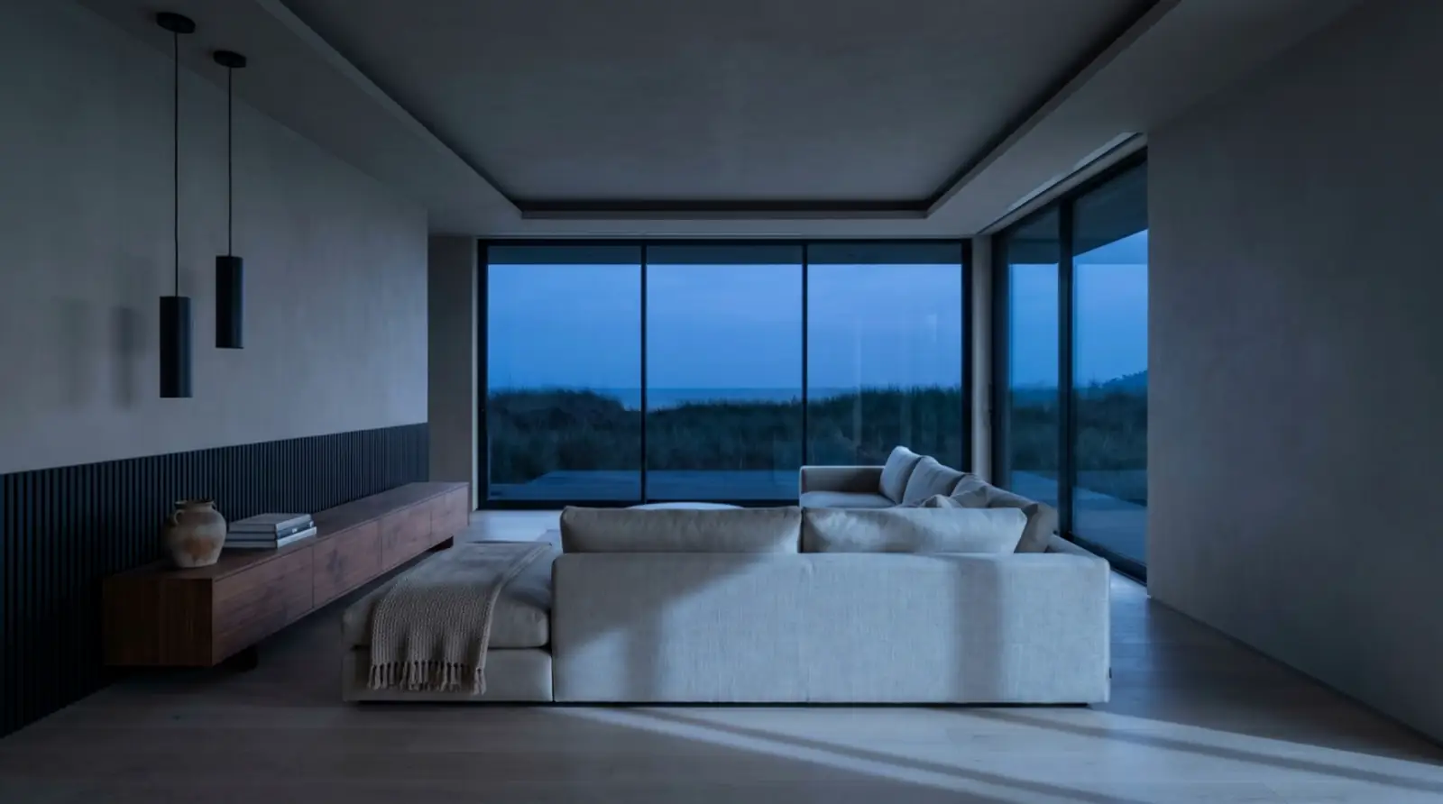 A coastal living room at dusk, before the lights come up.